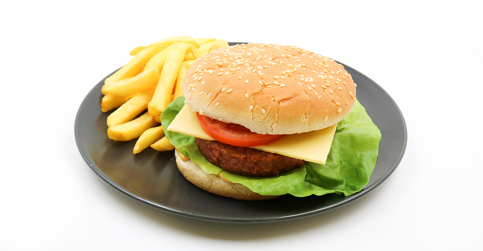 Veganer Burger mit Pommes Frites auf schwaren Teller.